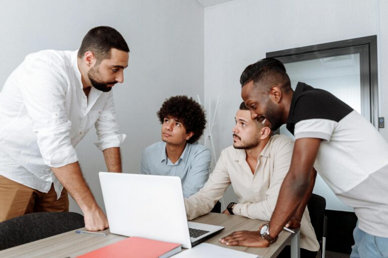 Diverse group of business professionals engaging in a collaborative meeting around a laptop.