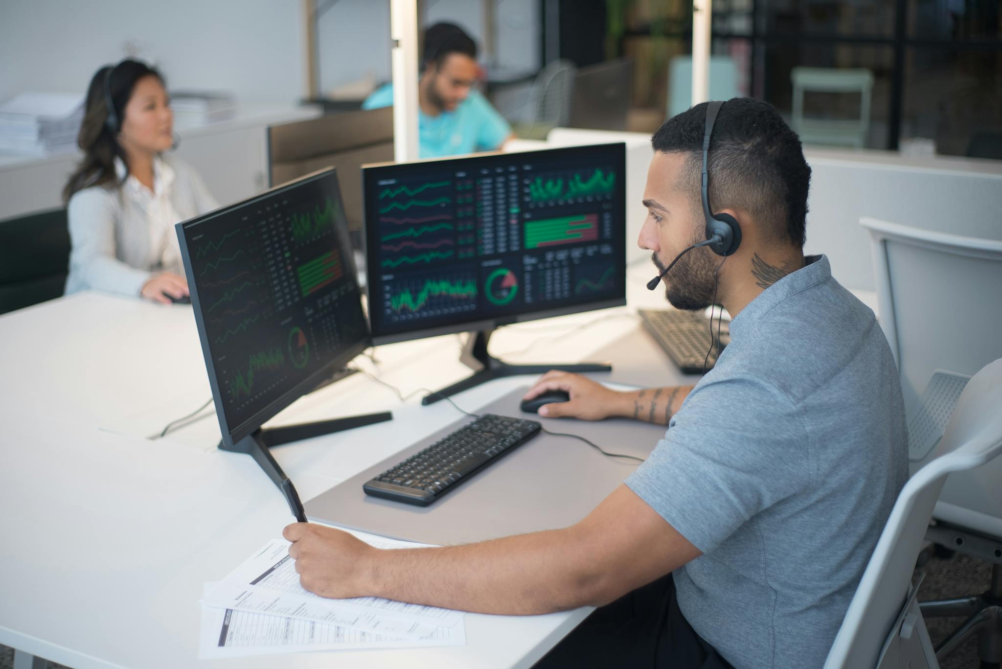 Team of customer service professionals working with headsets and computers in a modern office.